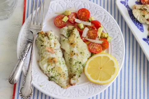 Deliciosa gallineta a la plancha con ensalada de tomate y aguacate, acompañada de un gajo de limón.
