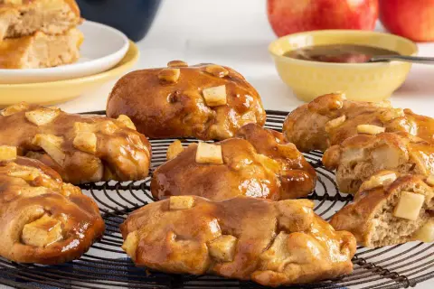 Buñuelos de manzana glaseados, con trozos de manzana visibles, sobre una rejilla.