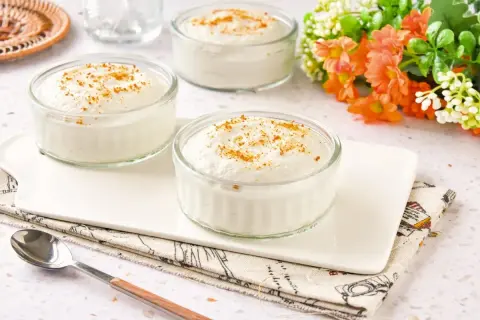 Tres ramequines de mousse de yogur con un toque de canela, servidos en una bandeja blanca.