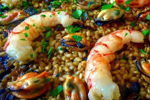 Arroz con gambas y mejillones, un plato lleno de sabor y color, con el arroz dorado y los mariscos frescos.