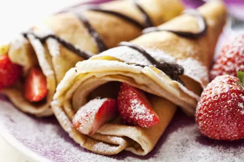 Deliciosos crepes sin huevo rellenos de fresas y bañados en chocolate, espolvoreados con azúcar glas.