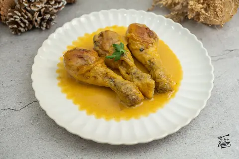 Tres jamoncitos de pollo dorados en una salsa cremosa, servidos en un plato blanco con un toque de perejil.
