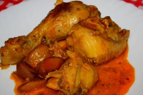 Sabroso pavo en salsa con cebollas, bañado en una rica y anaranjada salsa.