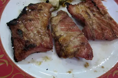 Tres trozos de lomo de cerdo al horno, jugosos y dorados, con sal gruesa y un borde ligeramente tostado.