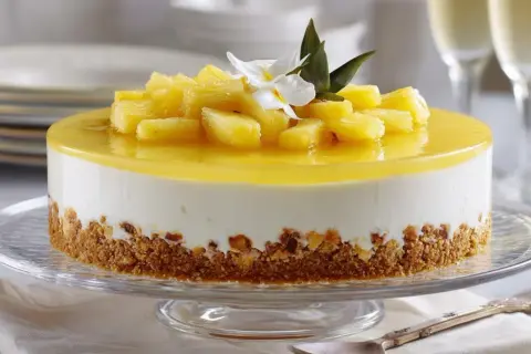 Deliciosa tarta de piña con trozos de fruta fresca y una capa de gelatina amarilla brillante, sobre una base crujiente.