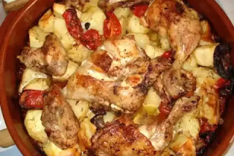 Rustidera de pollo dorada con patatas y pimientos asados, lista para servir.