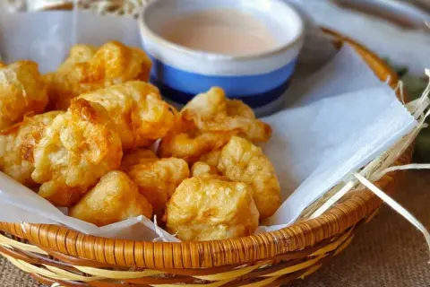 Fritos de rape crujientes y jugosos en una cesta con salsa.