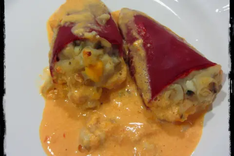 Dos pimientos del piquillo rellenos de gambas, cubiertos con una cremosa salsa rosada.