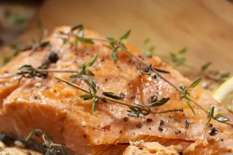 Delicioso salmón al horno, jugoso y dorado, con hierbas frescas y pimienta negra.