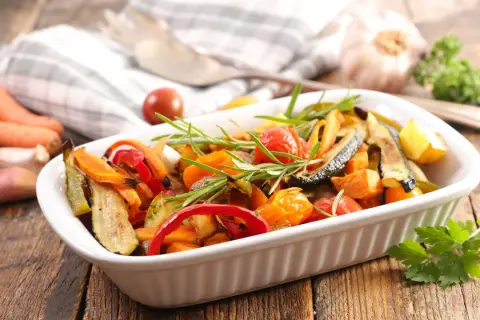 Deliciosas verduras al horno, como calabacín, pimientos y tomates cherry, con romero fresco, listas para servir.