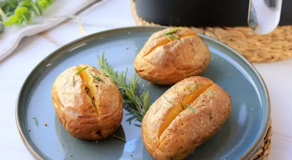 Tres patatas asadas airfryer doradas y crujientes, adornadas con romero fresco, listas para disfrutar.