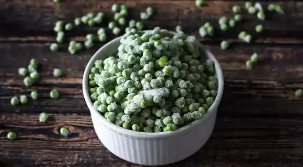 Un cuenco blanco lleno de guisantes congelados, perfecto para tus próximas recetas con guisantes congelados.