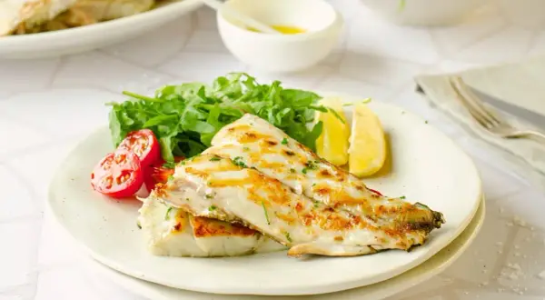 Deliciosa corvina a la plancha, servida con rúcula fresca, tomates cherry y gajos de limón. Un plato ligero y sabroso.