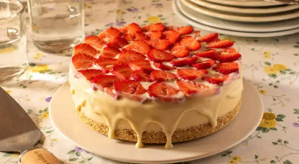 Tarta de frutas frescas cubierta de fresas y glaseado blanco cremoso.