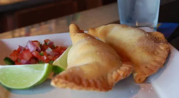 Dos empanadillas doradas con pico de gallo y limón. ¡Perfectos rellenos para empanadillas!