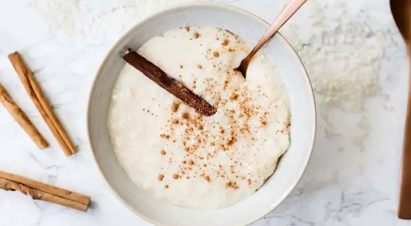 Un tazón cremoso de arroz con leche, espolvoreado con canela y una rama de canela. ¡Perfecto para aprender como hacer arroz con leche!