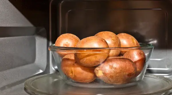 Patatas al microondas en un bol de cristal, listas para una cocción rápida y fácil.