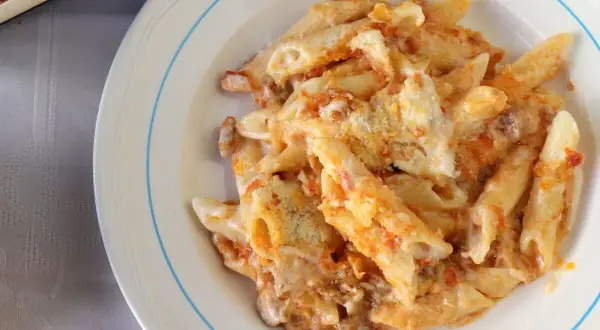 Un plato de macarrones del cardenal, cubiertos de salsa y queso, listos para disfrutar.