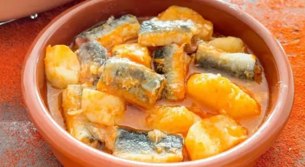 Un cuenco de barro con trozos de pescado y patatas en salsa, un delicioso all i pebre.