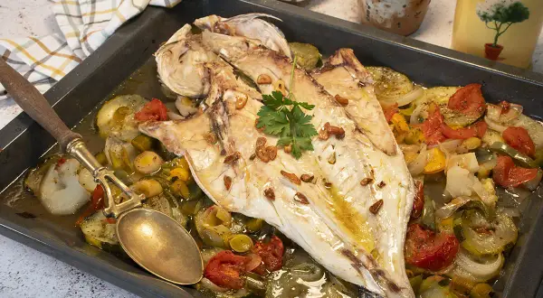 Lubina al horno con verduras asadas, ajo crujiente y perejil fresco. Un plato delicioso y saludable.