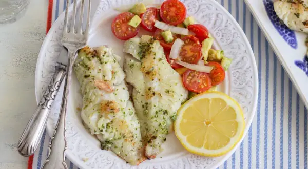Deliciosa gallineta a la plancha con ensalada de tomate y aguacate, acompañada de un gajo de limón.