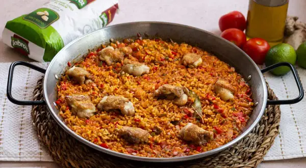 Paella de arroz con alitas de pollo, un plato lleno de sabor y color, listo para compartir.