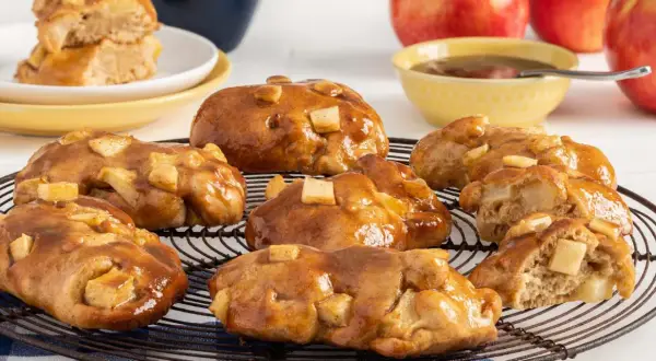 Buñuelos de manzana glaseados, con trozos de manzana visibles, sobre una rejilla.