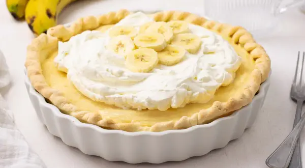 Delicioso pastel de plátano con crema batida y rodajas de plátano fresco. Un postre perfecto para cualquier ocasión.