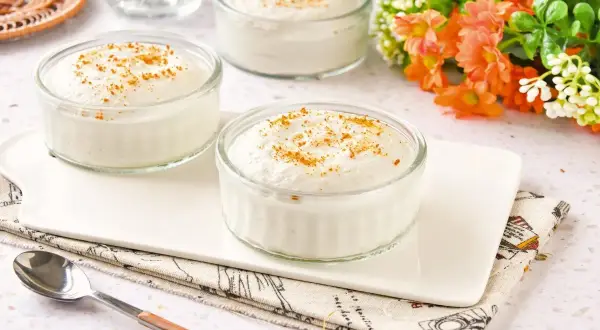 Tres ramequines de mousse de yogur con un toque de canela, servidos en una bandeja blanca.