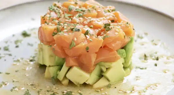 Delicioso tartar de salmón ahumado y aguacate, ideal para tus recetas con salmón ahumado. Adornado con sésamo y perejil.