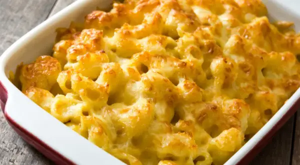 Mac and cheese cremoso y dorado, recién salido del horno en una fuente roja.