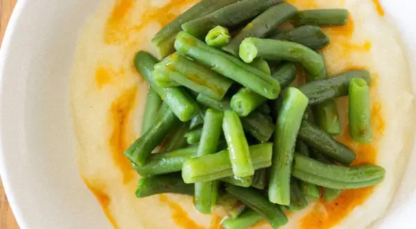 Judías verdes frescas y tiernas sobre un puré cremoso, con un toque de aceite de pimentón. Un plato sencillo y delicioso de judías verdes con patatas.