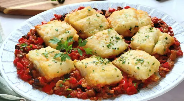 Bacalao con sanfaina: trozos de pescado blanco rebozado sobre una cama de pimientos rojos, berenjena y tomate.