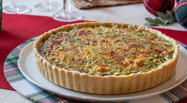 Un delicioso quiche de verduras con una corteza dorada y relleno cremoso, listo para ser disfrutado en una mesa festiva.