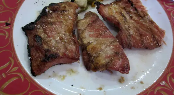Tres trozos de lomo de cerdo al horno, jugosos y dorados, con sal gruesa y un borde ligeramente tostado.