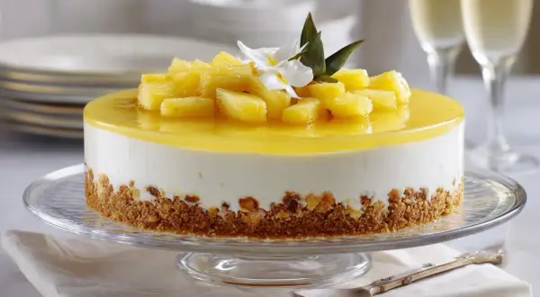 Deliciosa tarta de piña con trozos de fruta fresca y una capa de gelatina amarilla brillante, sobre una base crujiente.