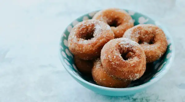 Rosquillas de Semana Santa espolvoreadas con azúcar, servidas en un cuenco azul.
