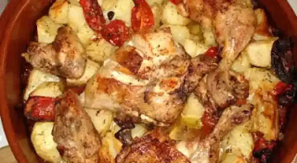 Rustidera de pollo dorada con patatas y pimientos asados, lista para servir.