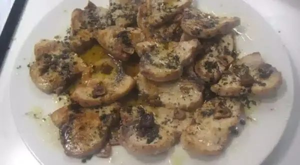 Delicioso emperador a la plancha, cortado en rodajas y servido con aceite de oliva y hierbas.