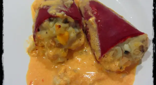 Dos pimientos del piquillo rellenos de gambas, cubiertos con una cremosa salsa rosada.