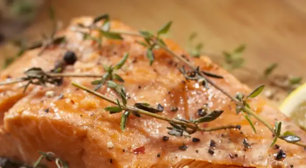 Delicioso salmón al horno, jugoso y dorado, con hierbas frescas y pimienta negra.