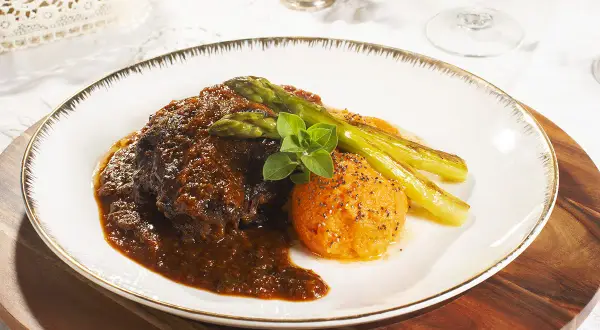 Carrilleras de ternera estofadas en salsa oscura, acompañadas de puré de boniato y espárragos trigueros.