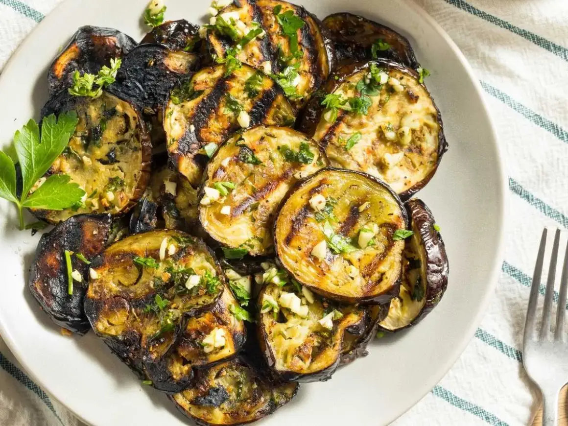 Rodajas de berenjenas a la plancha, doradas y tiernas, con ajo picado y perejil fresco. Un plato sencillo y delicioso.