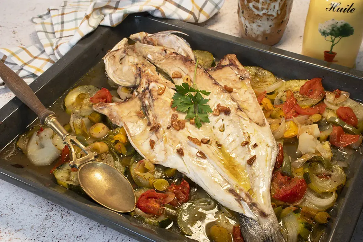 Lubina al horno con verduras asadas, ajo crujiente y perejil fresco. Un plato delicioso y saludable.