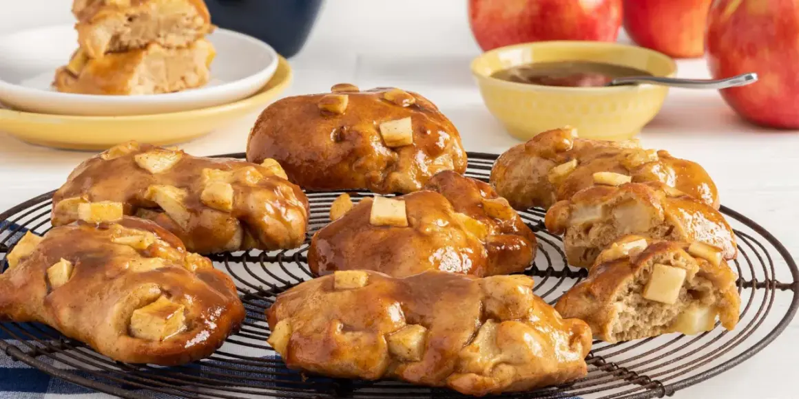 Buñuelos de manzana glaseados, con trozos de manzana visibles, sobre una rejilla.