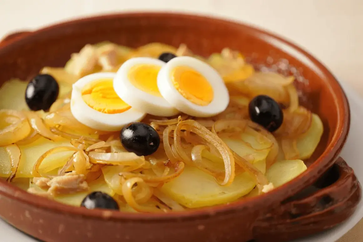 Bacalao a la portuguesa con patatas, cebolla, aceitunas negras y huevos duros en cazuela de barro.