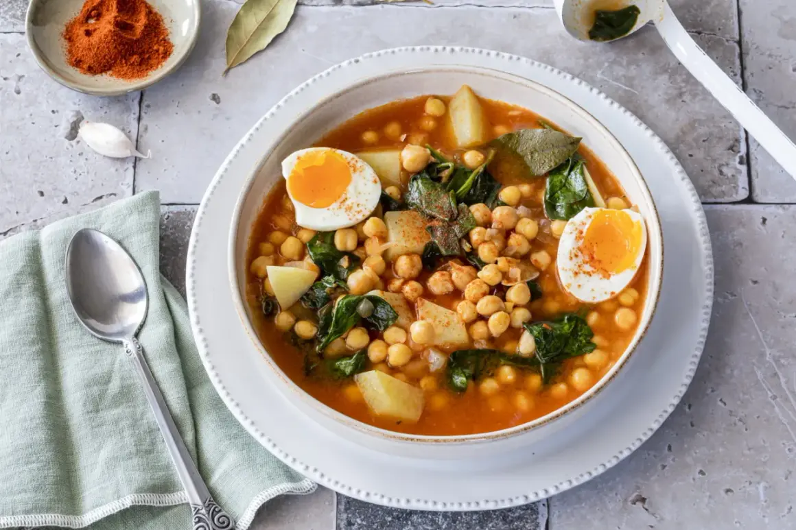 Un reconfortante plato de garbanzos con espinacas, patatas y huevos cocidos, espolvoreado con pimentón.