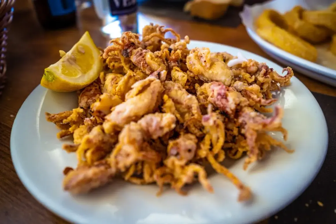 Plato de puntillas de calamar fritas, crujientes y doradas, servido con una rodaja de limón.