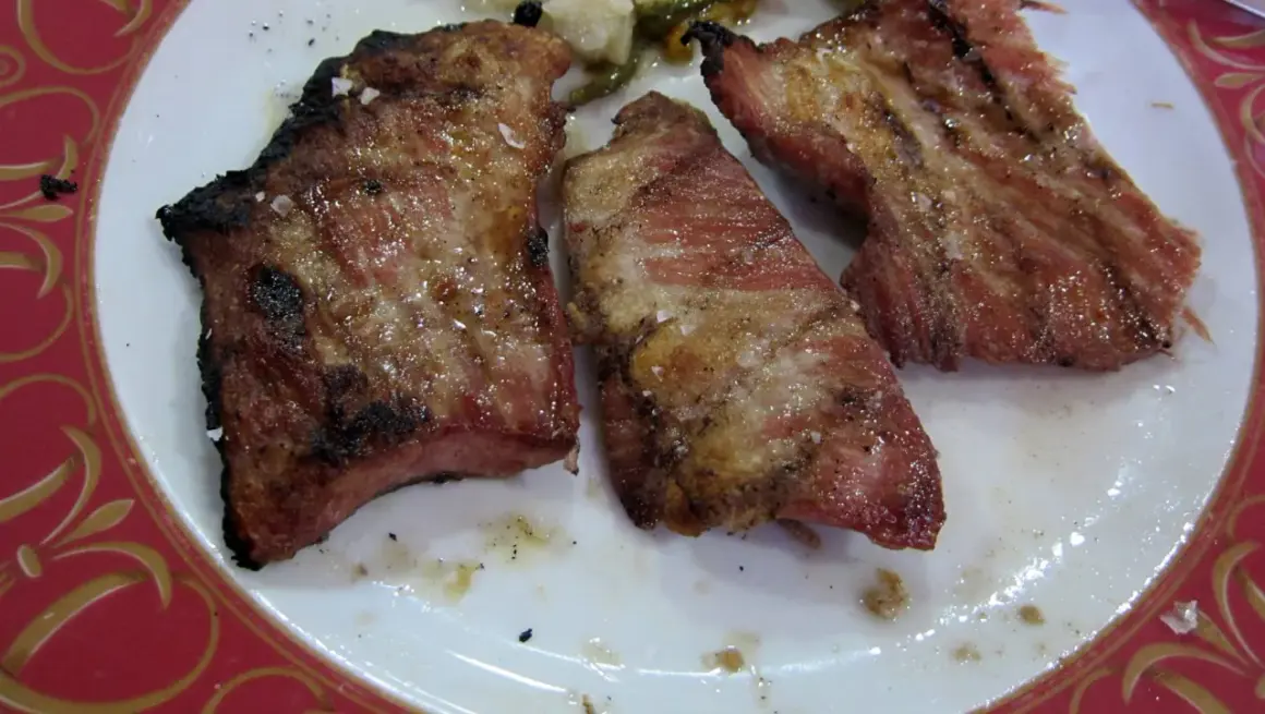 Tres trozos de lomo de cerdo al horno, jugosos y dorados, con sal gruesa y un borde ligeramente tostado.