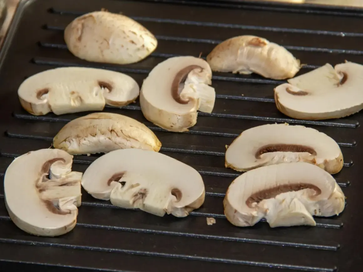 Champiñones cortados a la mitad y enteros sobre una parrilla, listos para deliciosas recetas con champiñones.